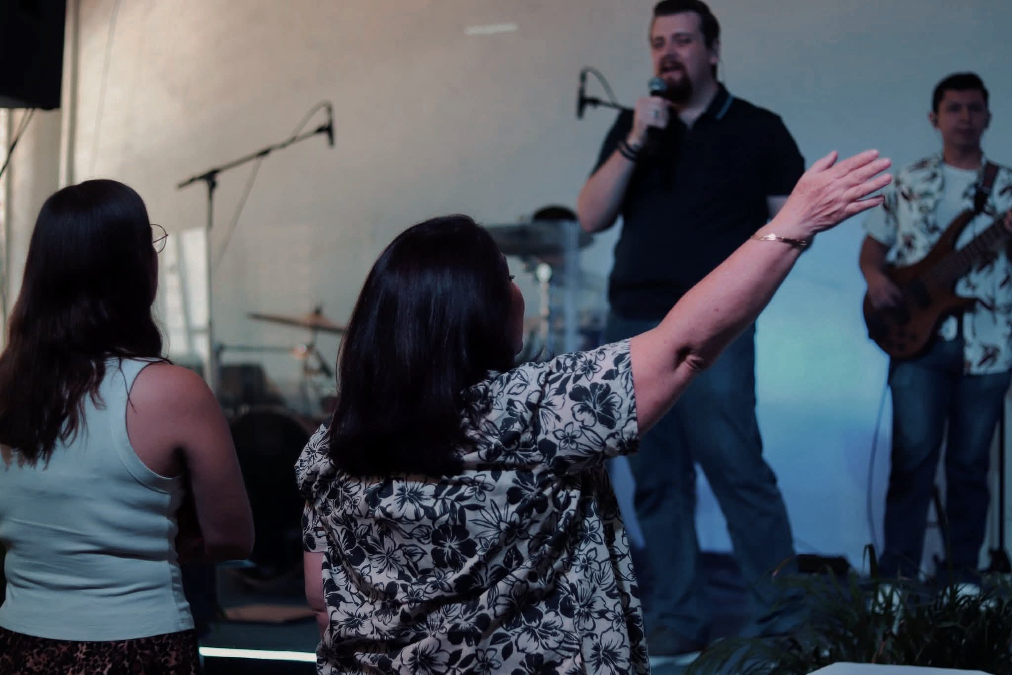 Mujer en adoración con el brazo levantado hacia el escenario